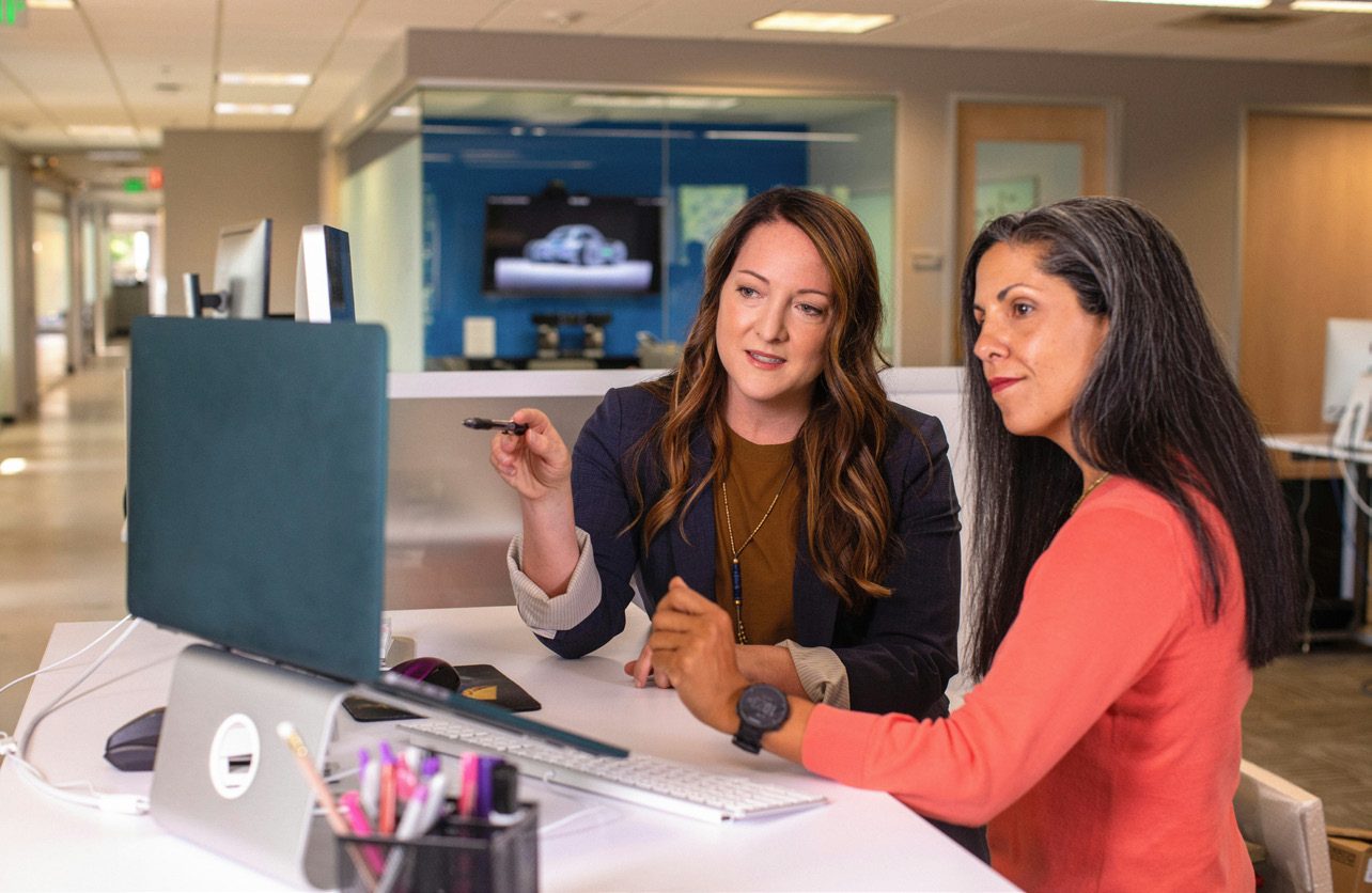 Two colleagues reviewing figures together on a laptop